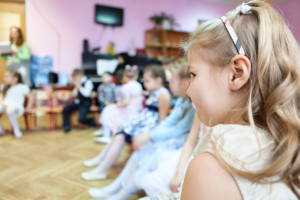 Small girl sitting in kindergarten class room at music lesson